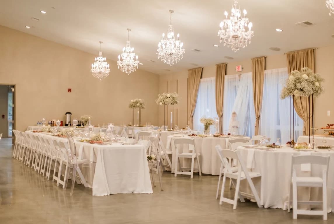 Grand Celebration package — long banquet tables with white linens and tall floral centerpieces under crystal chandeliers