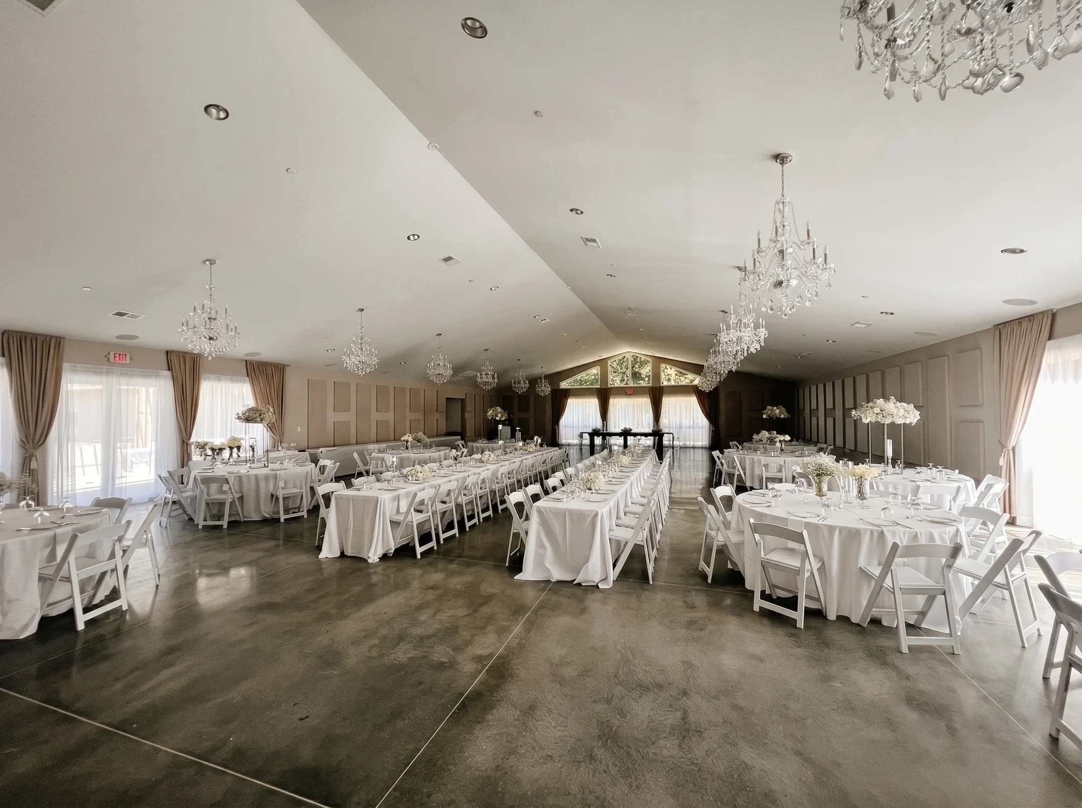Banquet tables and white folding chairs arranged around an open floor in the vaulted main hall at Fellowship Event Hall
