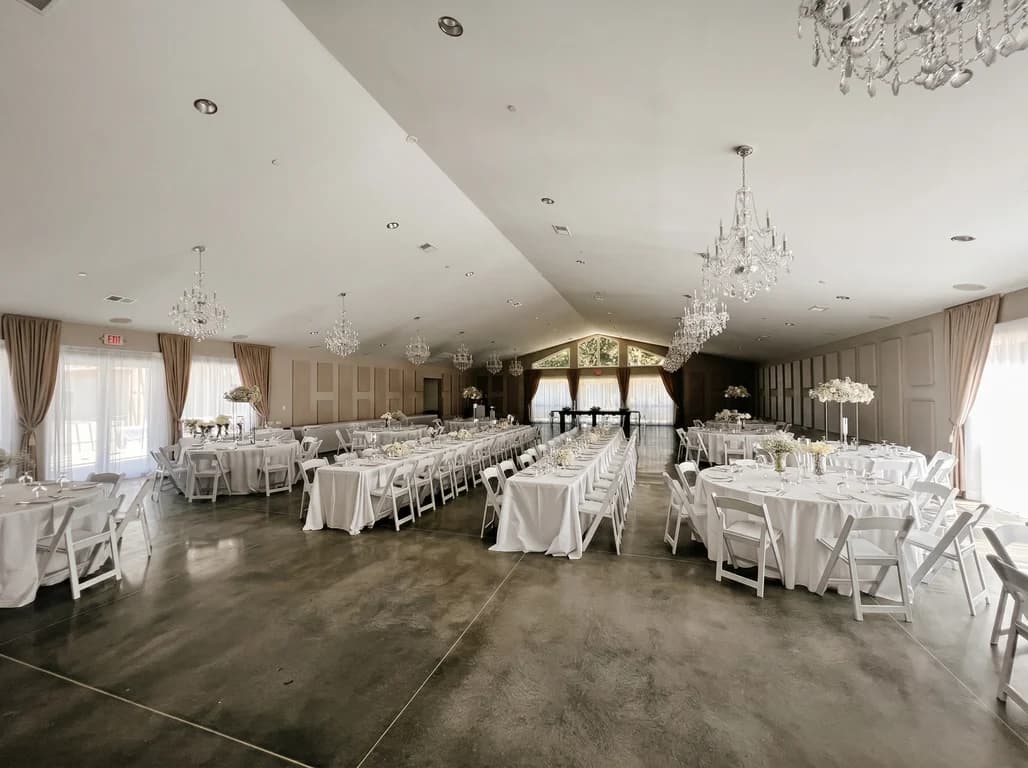 Banquet tables and white folding chairs arranged around an open dance floor in the vaulted main hall of Fellowship Event Hall in Dacula, GA