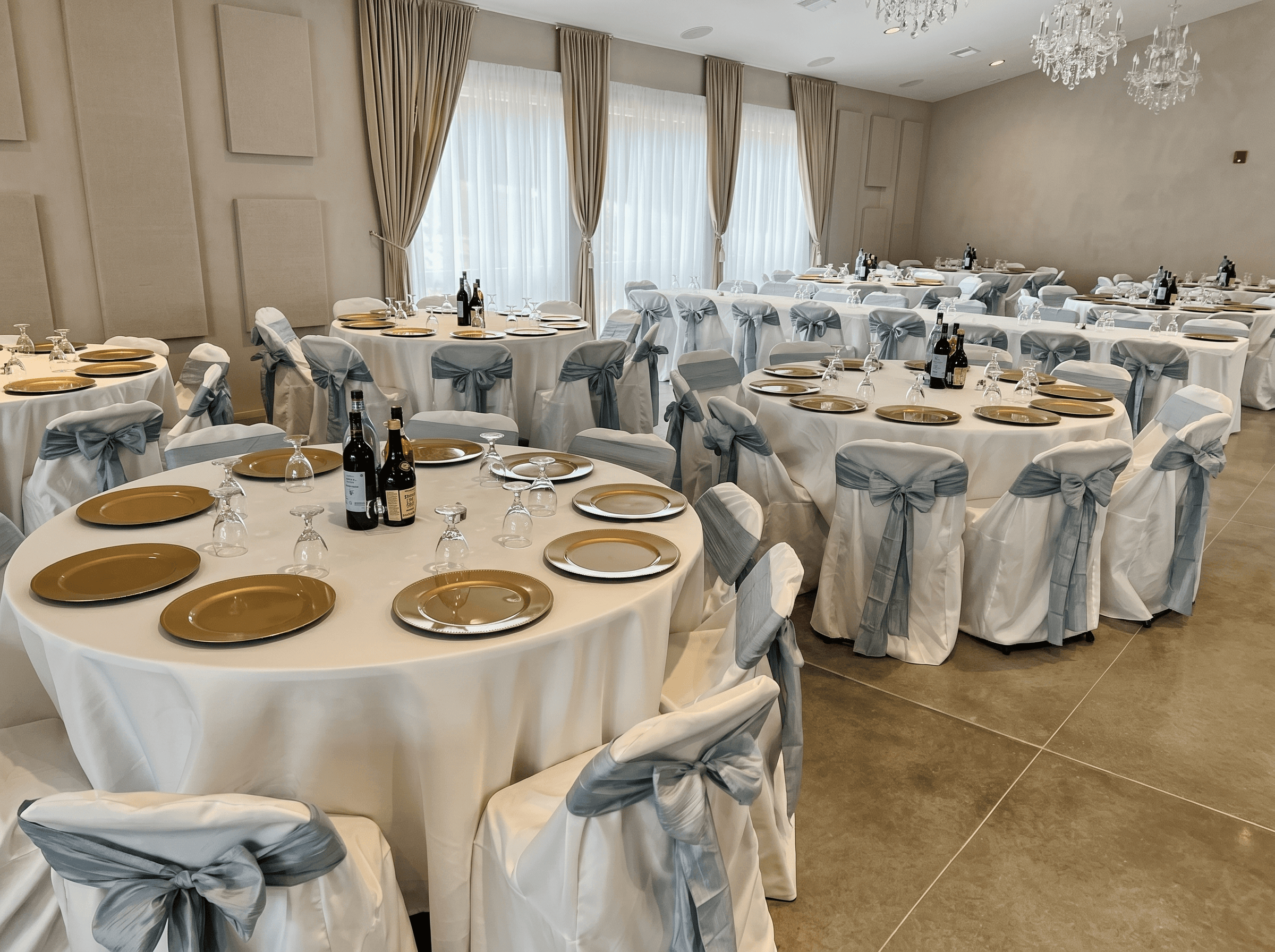 Main hall set up for a 150-guest wedding reception with round tables and linens